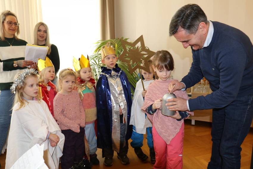 Das Bild zeigt den Landrat, wie er den Sternensingern, die vor ihm stehen, Geld in die Spendenspardose steckt. Das Bild zeigt den Landrat, wie er den Sternensingern, die vor ihm stehen, Geld in die Spendenspardose steckt.