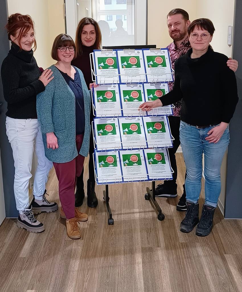 Mitarbeitende der Betreuungsbehörde stehen neben einem Aufsteller mit Infomaterial.