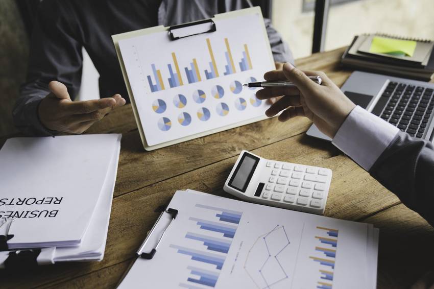 Auf einem Tisch sind Abbildungen von Diagrammen. Eine Hand zeigt auf diese Diagramme. Auf einem Tisch sind Abbildungen von Diagrammen. Eine Hand zeigt auf diese Diagramme.