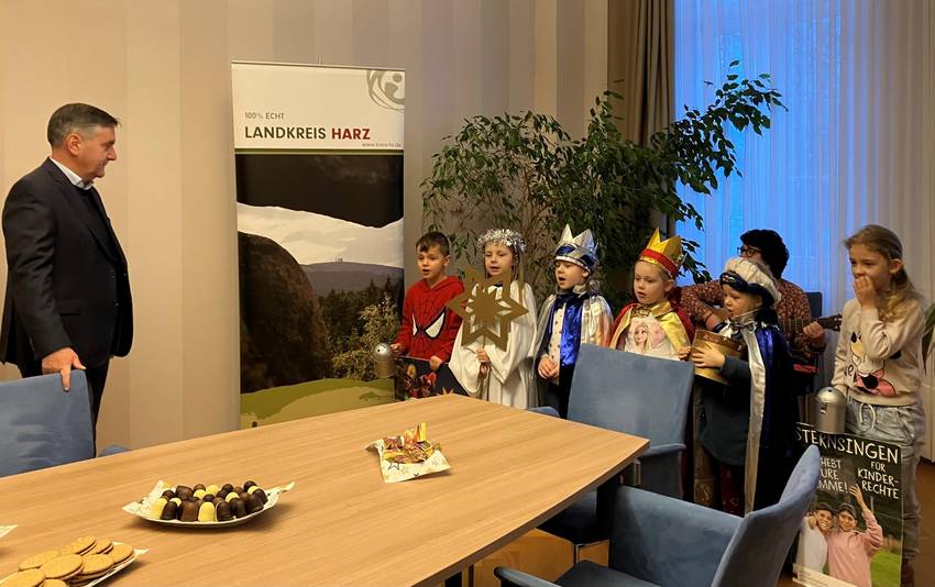 Kinder, die als Sternsinger verkleidet sind, stehen dem Landrat Thomas Balcerowski gegenüber. Kinder, die als Sternsinger verkleidet sind, stehen dem Landrat Thomas Balcerowski gegenüber.