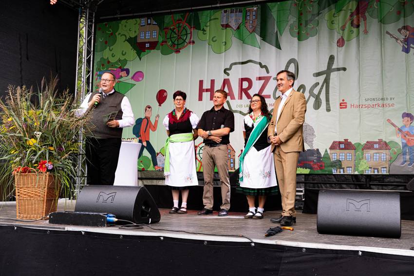 Bürgermeister Heiko Breithaupt, Landrat Thomas Balcerowski und weitere Personen auf der Bühne beim Harzfest in Hüttenrode. © Marvin Mikulla