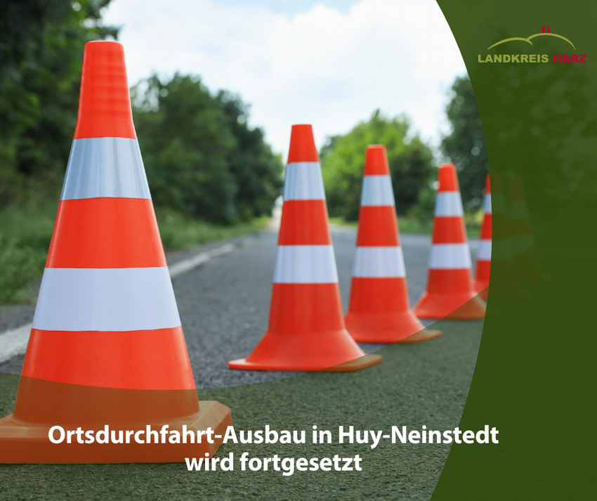 Apserrpylonen auf einer Straße. Im unteren Teil ein grüner Bereich mit der Aufschrift Ortsdurchfahrt-Ausbau in Huy-Neinstedt wird fortgesetzt.