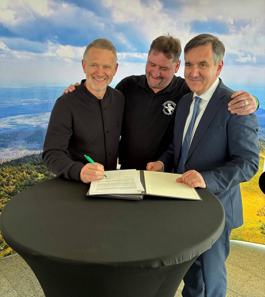 von links nach recht: Geschäftsführer Thomas Kemner on Timberjacks, ehemaliger Brockenwirt Daniel Steinhoff und Landrat Thomas Balcerowski. Vor den drei Herren steht ein Tisch, auf dem Der Pachtvertrag liegt.