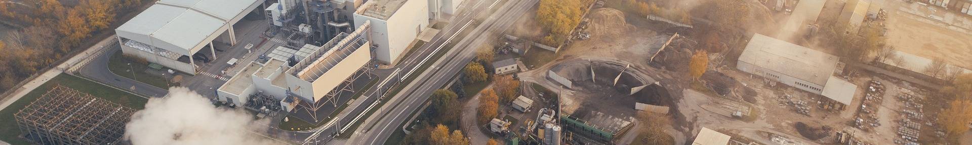 Industriegebiet von oben mit aufsteigendem Qualm aus einem Anlagenturm