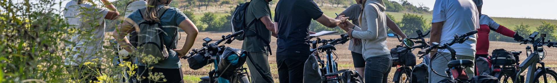 Mehrere Personen mit Fahrrad und Helm, im Hintergrund die Teufelsmauer beim Marienhof