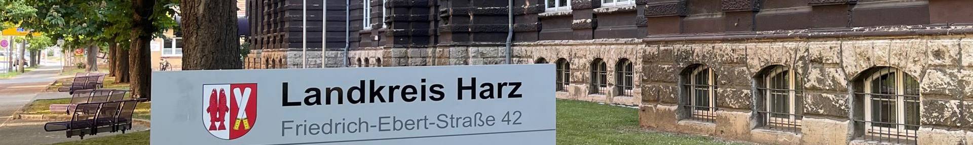 Außenansicht Verwaltungsgebäude Landkreis Harz, im Vordergrund ein Schild mit Öffnungszeiten.