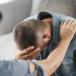 Das zeigt zwei Menschen bei einer Beratung und ein Mensch hat den Kopf auf seinen Arm gelegt