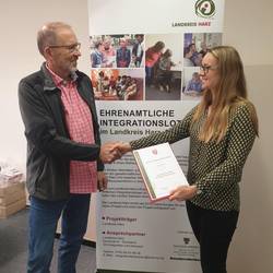 Susanne Reinhardt von der Koordinierungsstelle für Migration und Ehrenamt übereicht Klaus Mansfeldt seine Ernennungsurkunde.