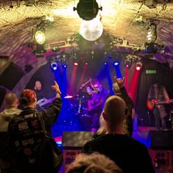 Tanzende Menschen vor einer Bühne mit bunten Lichtern in einem Party-Keller. Tanzende Menschen vor einer Bühne mit bunten Lichtern in einem Party-Keller.