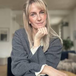 Auf dem Bild ist Esther Jödecke zu sehen, sie trägt eine graue Strickjacke und hat ihre blonden bis über die Schulter langen Haare leicht zusammengesteckt
