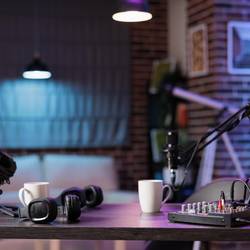 Keine Menschen an einem leeren Schreibtisch mit Aufnahmetechnik und zwei Podcast-Mikrofonen mit zwei Kaffetassen an den Arbeitsplätzen