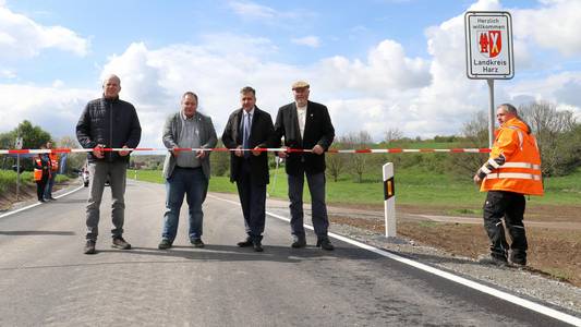 Menschen, die auf einer Straße stehen und ein Band durchschneiden