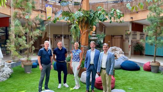 Das Foto zeigt mehrere Personen, die auf einem Rasen stehen und von einzelnen Kiefern umgeben sind.