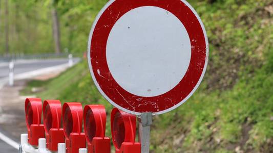 Durchfahrt verboten Verkehrsschild vor einer Absperrbake auf einer Straße.