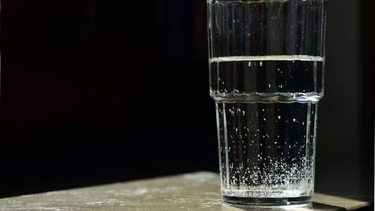 Wasserglas mit Wasser drin auf einem Tisch.