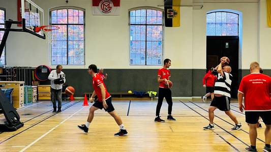 Auf dem Bild sind mehrere Spieler abgebildet, die zusammen Basketball spielen.