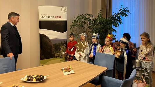 Kinder, die als Sternsinger verkleidet sind, stehen dem Landrat Thomas Balcerowski gegenüber.