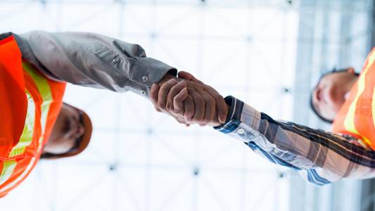 Zwei Männer geben sich die Hand - Perspektive von unten.