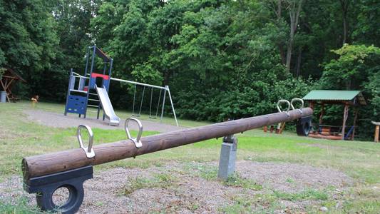 Spielplatz Ein Spielplatz. Im Vordergrund steht eine Wippe, im Hintergrund ein Kletterturm mit Rutsche.