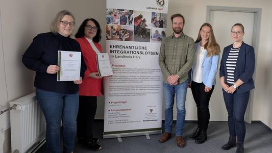 Zwei Integrationslotsen mit ihren Berufungsurkunden. und dem Team der Koordinierungsstelle.