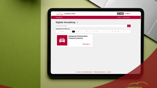 Tablet auf einem grünen Hintergrund. Im Tablet die Ansicht des Onlinedienstes Antrag auf Führerscheinumtausch. Im unteren Teil ein roter Bereich mit der Aufschrift Führerscheinumtausch ist im Landkreis Harz jetzt auch online möglich.