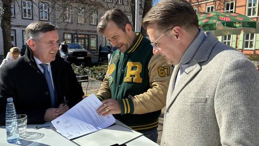 Von links nach rechts: Landrat Thomas Balcerowksi, Karls-Vhef Robert Dahhl und Wernigerodes Bürgermeister Tobias Kascha stehen gmeinsam an einem Tisch. Herr Dahl hat die Baugenehmigung des Landkreises Harz vor sich liegen und blättert diese durch.