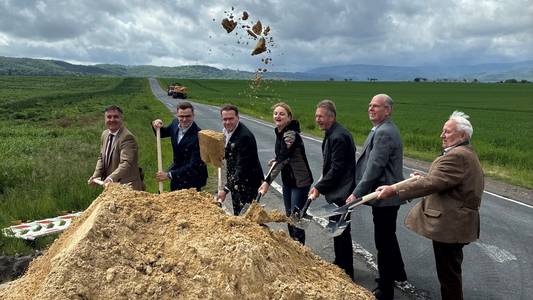 Baustart für neue Radwegeverbindung bei Wernigerode Gruppenfoto mit mehreren männlichen Perosnen, die einen Spaten in der Hand hlaten und hinter einem Sandberg stehen. Im Hintergrund sind Häuser und ein grüner Bagger.