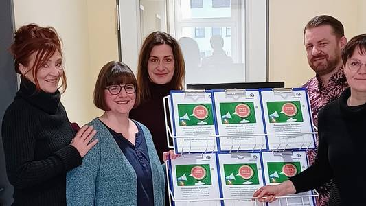 Fünf Menschen stehen in einem Raum und zeigen ein Schulungsprogramm