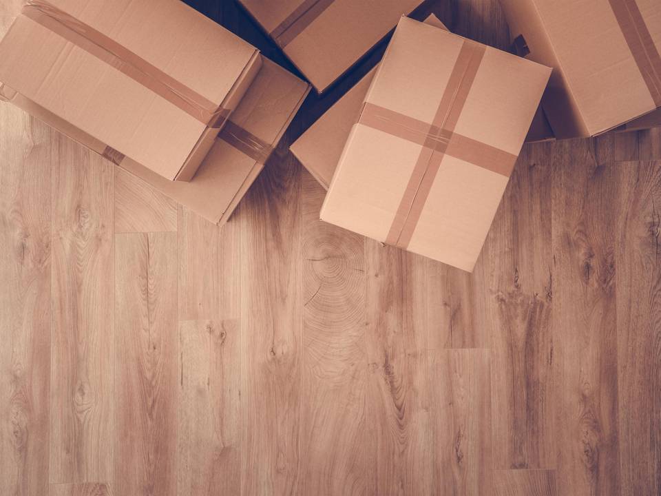Umzugskartons, die auf einem Holzfußboden stehen.